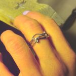 Propletený prsten z drátků zdobený kuličkami je vyfocen na prstu